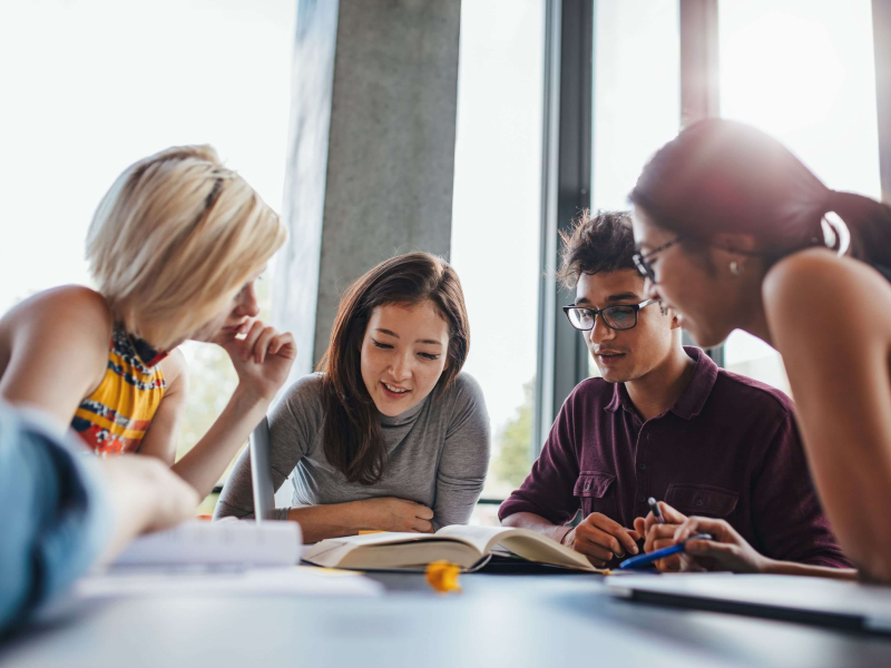 Students sitting around a table smiling 