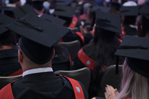 Graduands sat in ceremony hall with graduation caps