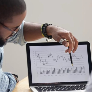 Two people looking at charts on a laptop screen