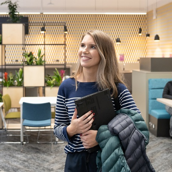 Student holding laptop in student study space
