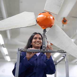 Student in lab coat interacting with a prototype turbine